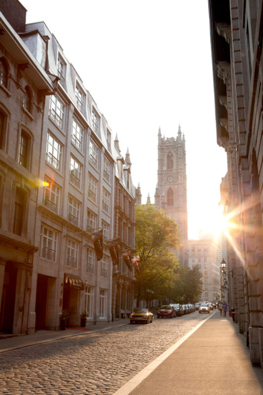 Vue du Saint-Sulpice Hotel Montreal depuis la rue, avec la Basilique Notre-Dame en arrière-plan