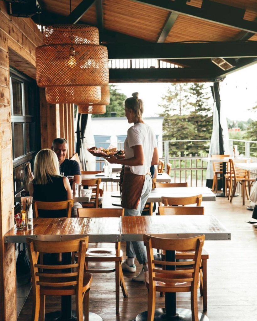 restauratrice qui sert un plat à des clients en terrasse