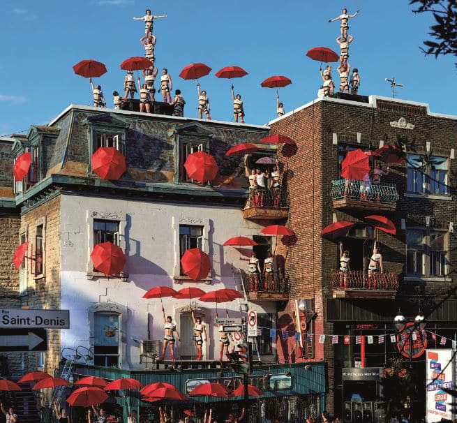 © Andrew Millet : dans une rue de Montréal, au sol, en l'air et même sur les toits, le cirque propose un spectacle accompagné de leur parapluie.