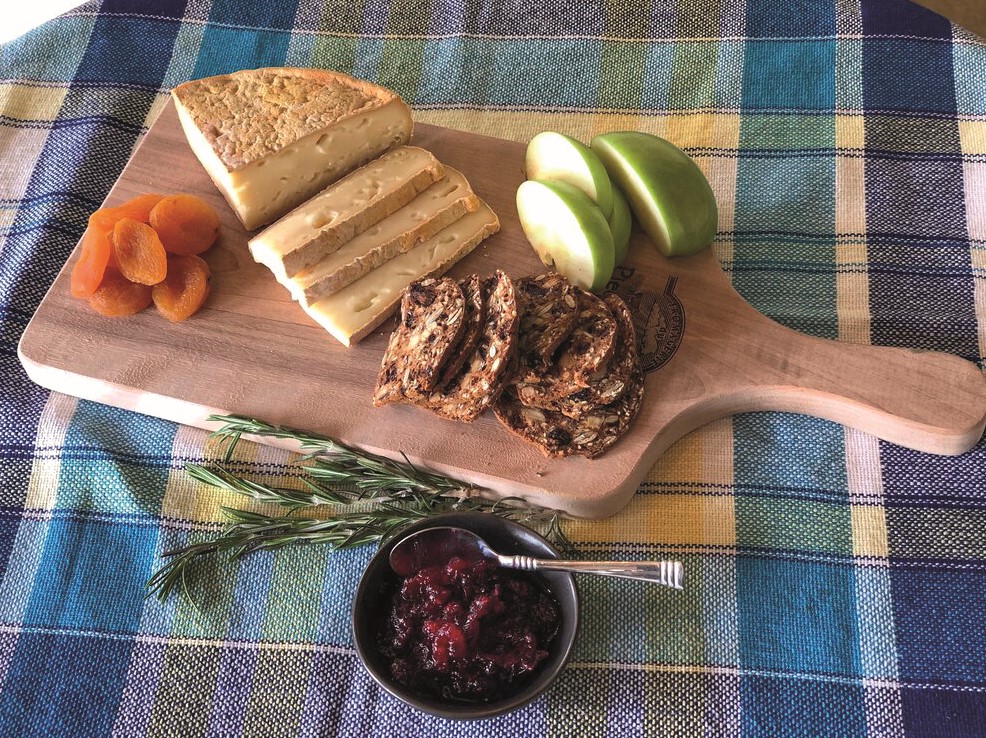 © Fromagerie Pied-de-Vent : planche en bois avec du fromage, des fruits secs, une pomme et du pain au céréale