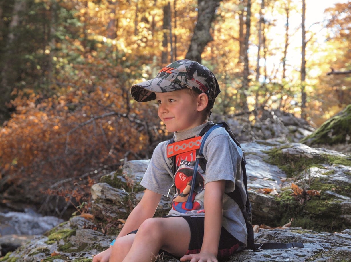 © Québec Original : enfant assis sur un rocher dans la forêt