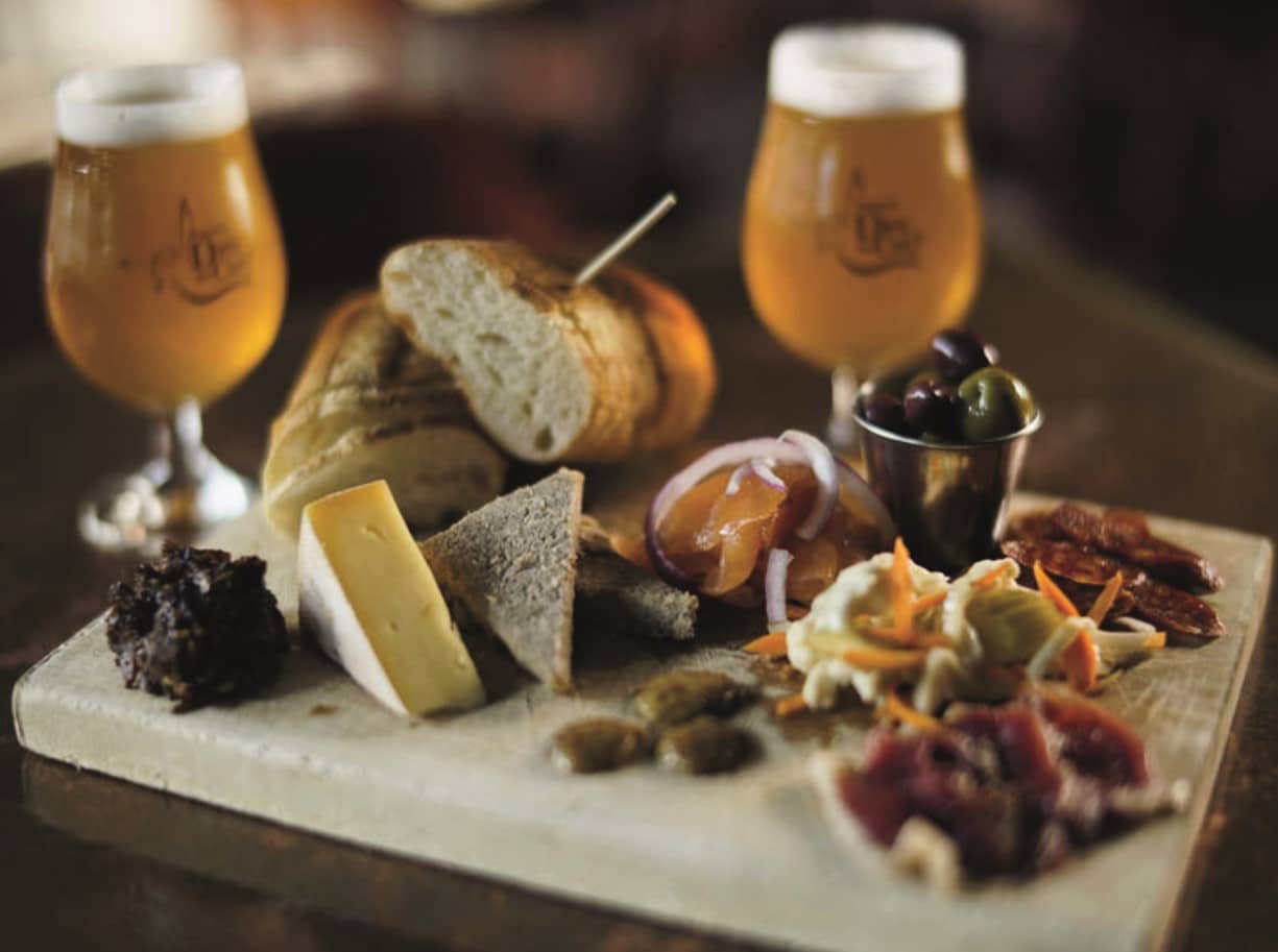 © Tourisme Laurentides : assiette de charcuterie et fromage accompagnée de deux bières