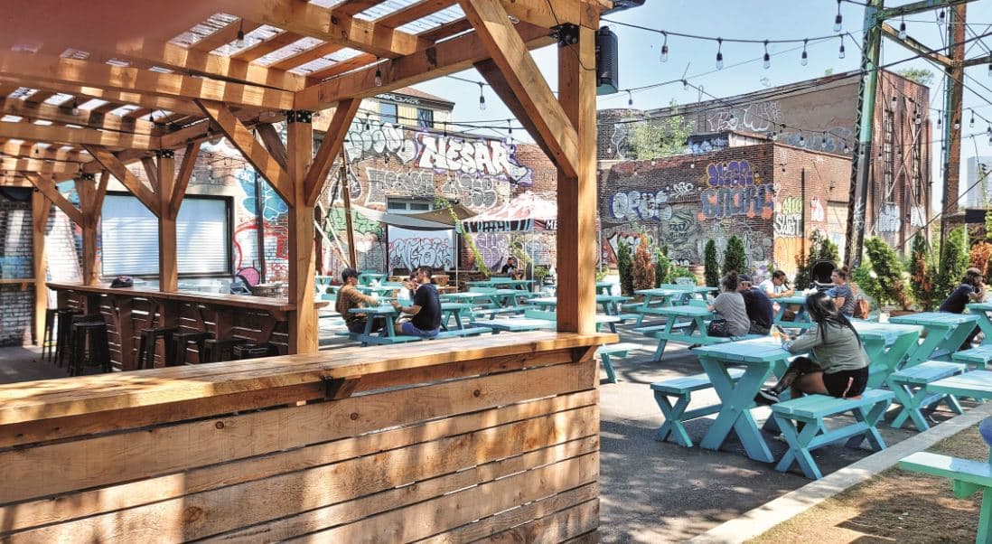 Valérie Fortier : grande terrasse avec ses tablées en bois colorées bleu et ses graffitis qui recouvrent les murs.