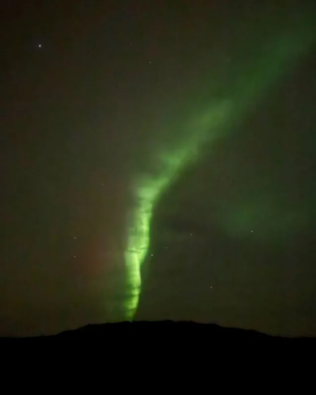 SAFARI ARCTIQUE AU NUNAVIK
📍JOUR 8, Lac Wolf | 10°C

Preuve que la toundra arctique nous plonge dans un tout autre espace-temps, on a un mal fou à réaliser que six journées viennent de s'écouler au lac Wolf. Comme pour nous retenir encore au plus près de la vie du camp, la météo décide qu'il n'y aura pas d'excursion aujourd'hui. De bout en bout du voyage, le ciel aura été le chef suprême, suivi de près par Allen Gordon, notre hôte et guide inuit. 

Jusqu'au dernier moment, Allen partage avec le groupe ses connaissances sur la toundra, sur la réalité implacable du nord (le vent et les ours ont infligé de lourds dégâts au camp l'hiver passé) et sur l'histoire et les traditions des Inuit. La journée se partage entre des récits au chaud, dans la cabane principale, à feuilleter d'albums photo où les aïeux d'Allen, encore nomades, apparaissent en tenues traditionnelles, et des petites sorties autour du camp pour ramasser quelques baies et feuilles de thé du Labrador.  À table, l'omble chevalier régale l'assemblée. Un poisson qui peuple les eaux du lac Wolf aux côtés de la fameuse truite grise, ou touladi. 

Alors que la nuit s'est déjà installée, on plaisante sur le fait qu'il n'aura manqué que le spectacle des aurores boréales au séjour. Quand on regagne notre petit chalet, un peu penauds et déjà nostalgiques, ce qui semble être des nuages plus clairs que les autres nous intriguent. Camyanne accoure avec un grand sourire : "Les voilà ! Elles arrivent ! Le dernier soir, comme prévu." D'abord timides, les "northen lights" se font de plus en plus nettes, de plus en plus vertes, dessinant un grand arc lumineux au-dessus du lac. Camyanne allume un feu et nous restons en hypnose jusqu'à près de 23 heures devant le ballet silencieux. Allen nous rejoint. Quand j'approche mes mains du feu pour les réchauffer, il nous confie que petit, ses parents lui interdisaient de faire ce geste, "car les Inuit doivent apprendre à ne pas avoir froid aux mains". Un autre monde, on vous dit. Impitoyable et magique à la fois. 

Cette dernière nuit sur la toundra s'annonce remplie de rêves...
.
.
#quebeclemag #quebec #qc #nunavik #nunawild #explorequebec #nunaviklife